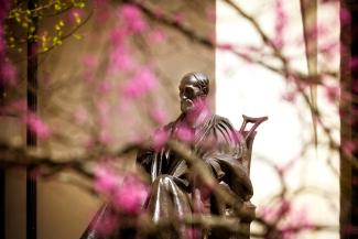 President Patterson bronze statue surrounded by pink flower buds from the trees in spring