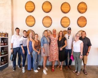 Bourbon barrel lids hung on a wall, line of smiling people posing in front