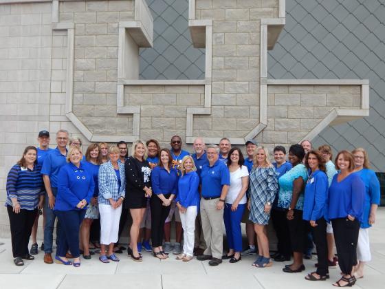 Parent Advisory Council members standing together in front of a large concrete UK