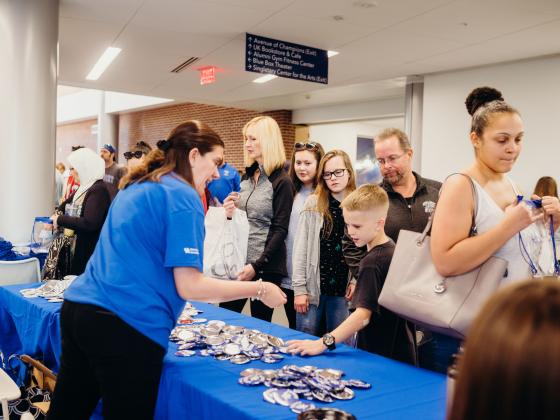 UK staff members handing Family Weekend buttons to a child