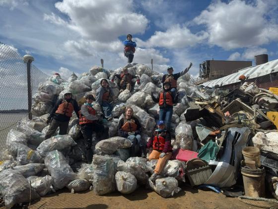 Pile of full trash bags with students sitting on top